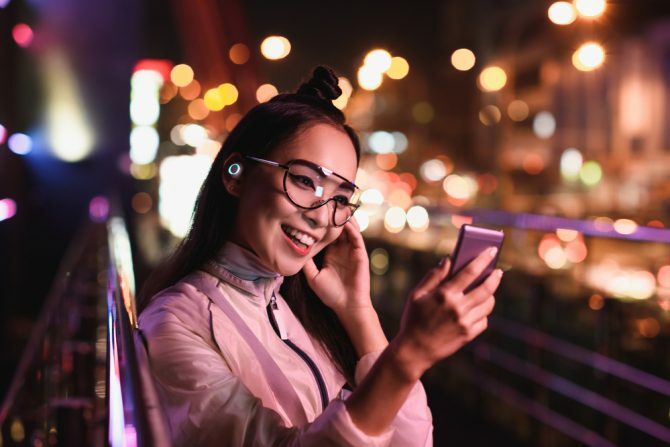 boldog ázsiai lány videocsevegés használ smartphone és a fülhallgató